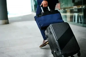 businessman pulling rolling suitcase