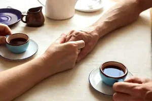 couple holding hands drinking coffee
