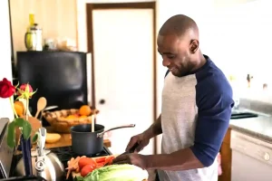 happy man standing in kitchen preparing food