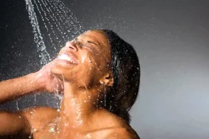 water from shower splashes on face of woman