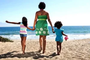 woman and two girls holding hands on the beach 3